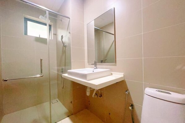 A modern bathroom with a glass shower enclosure, a white sink, and a mirror above it. - GYDEN STAYCATION #Green Haven near Senibong&Regency (Plentong)