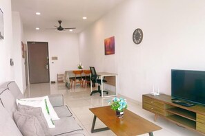 A modern living room with a sofa, coffee table, TV stand, and a dining area with chairs and a table. - GYDEN STAYCATION #Green Haven near Senibong&Regency (Plentong)