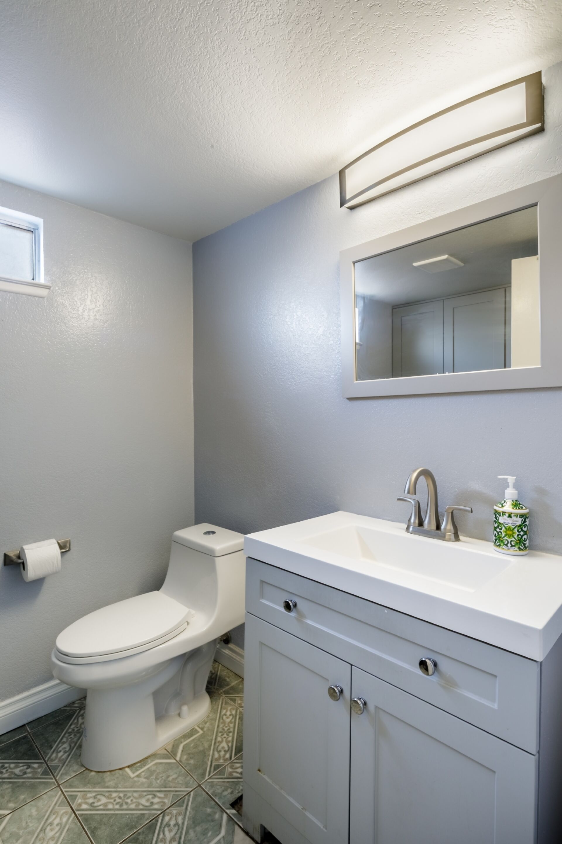 A bathroom with a toilet, sink, and mirror.