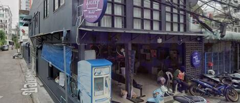 A building with a signboard, a blue scooter, and a motorcycle parked outside.