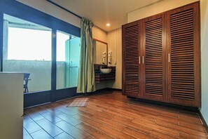 A room with a large sliding glass door, a wooden wardrobe, a sink, and a small table. - The Loft Hostel by Evernent (Miri)