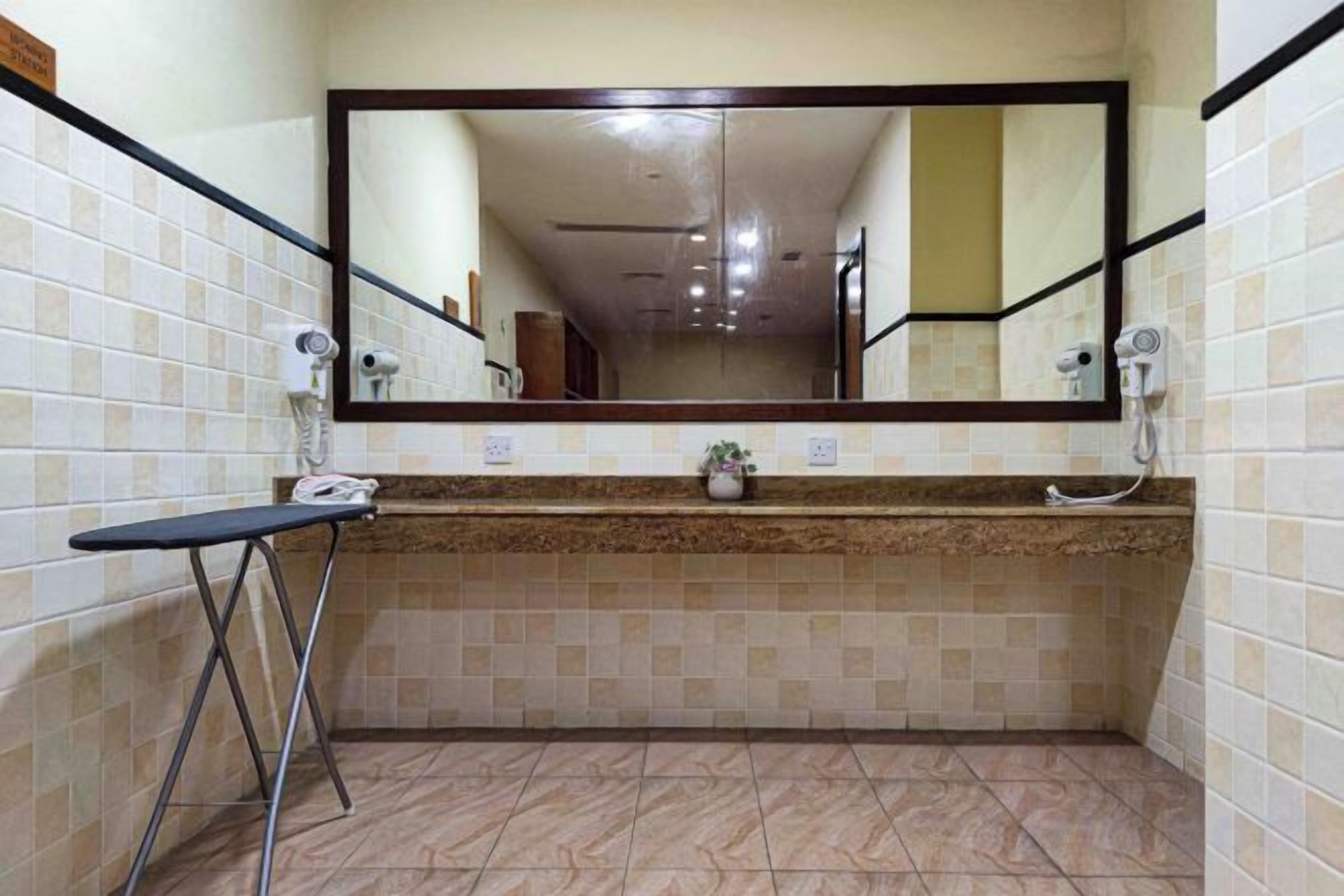 A bathroom with a large mirror, a sink, and a hairdryer.