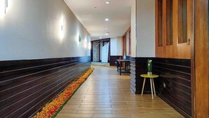 A hallway with wooden paneling, a tiled floor, and a small table with a vase. - The Loft Hostel by Evernent (Miri)
