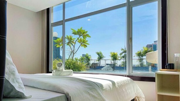 A hotel room with a large window, a bed, a bedside table, and a lamp. - The Loft Hostel by Evernent (Miri)