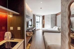 Una habitación de hotel moderna con kitchenette, cama, zona de estar y vistas a la ciudad.