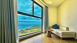 A room with a large window, a sofa, and a small table. - Mandala Heaven Dreamscape Hotel & Resort (Phan Thiet)