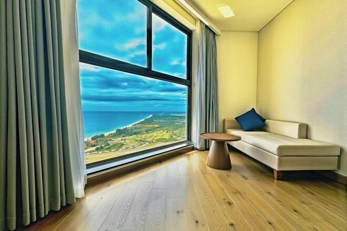 A room with a large window, a sofa, and a small table.