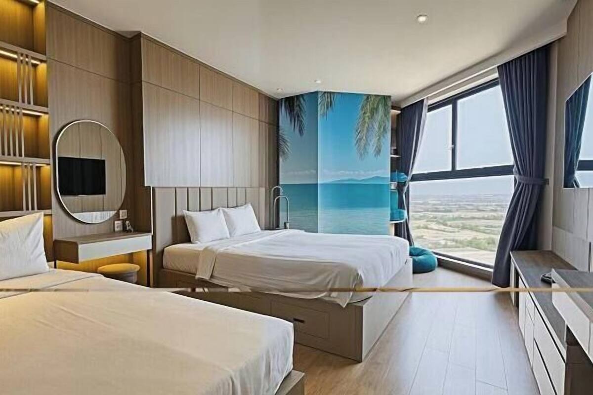 A hotel room with two beds, a large window with a view, a mounted TV, and a wall-mounted mirror.