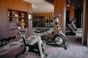 Une salle de sport équipée de vélos d’appartement et d’appareils de cardio, avec un lambris en bois et un sol à motifs.