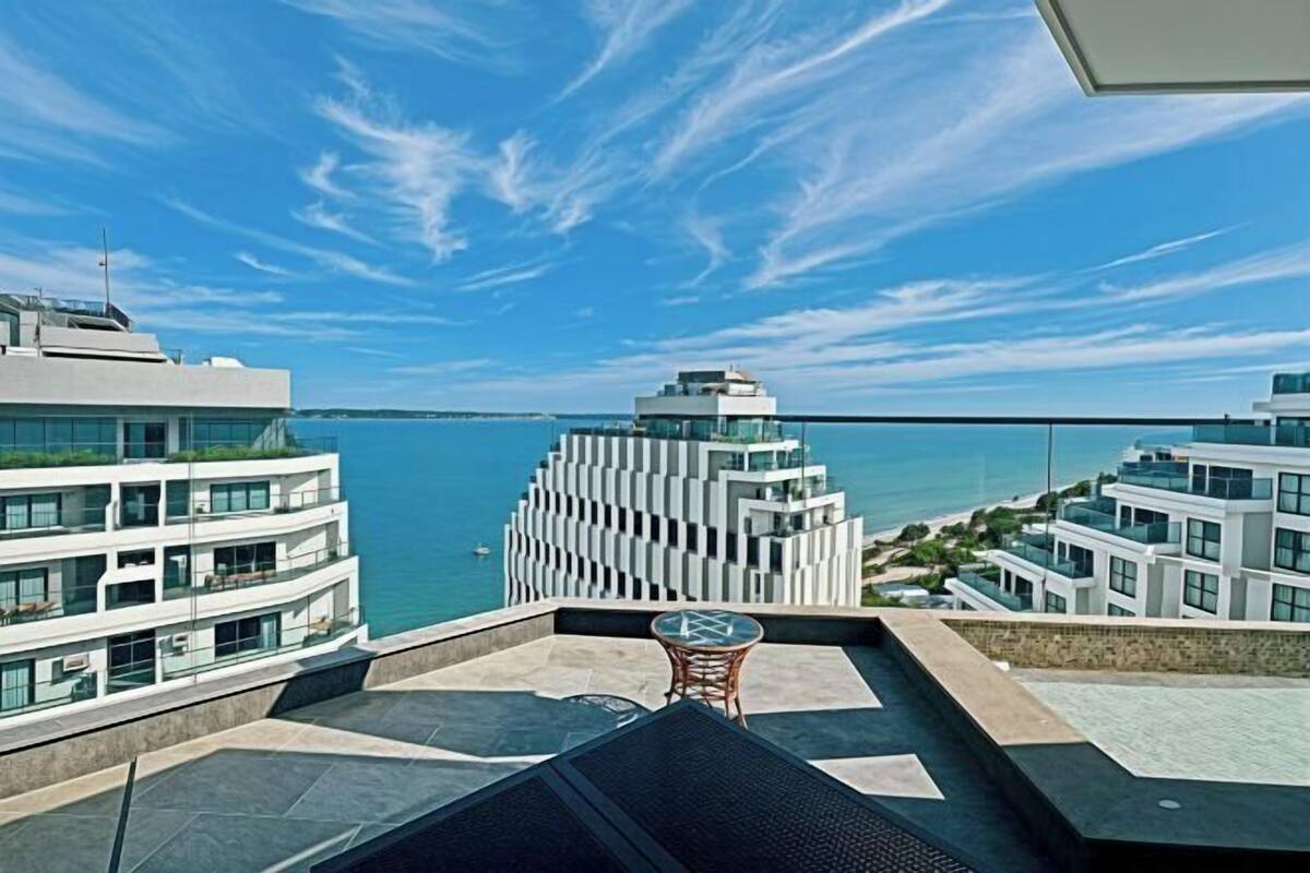 A modern building with a glass facade overlooking a body of water.