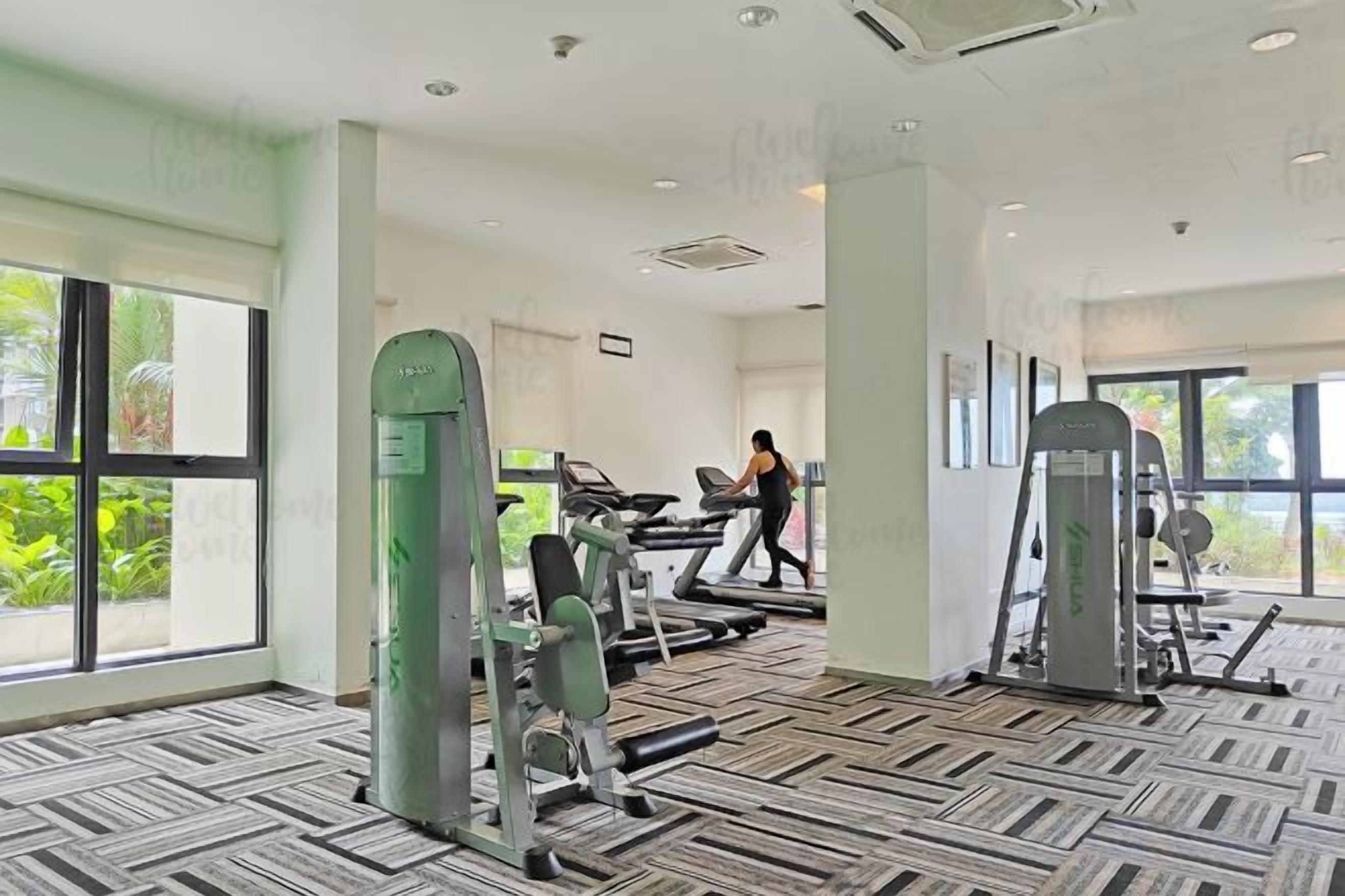 A gym with treadmills, weight machines, and a person exercising.