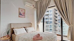 A bedroom with a bed, a bedside table with a plant, a wall-mounted air conditioner, and a window with curtains. - Amberside, Country Garden Danga Bay Homestay by Welcome Home (Johor Bahru)
