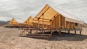 A row of wooden cabins with white canopies, set in a desert landscape. - Pana Unique Charyn (Enbekshikazakh District)