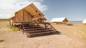A desert-style hotel with a large open-air structure, wooden benches, and a clear view of the surrounding landscape. - Pana Unique Charyn (Enbekshikazakh District)