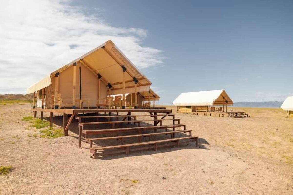 A desert-style hotel with a large open-air structure, wooden benches, and a clear view of the surrounding landscape.