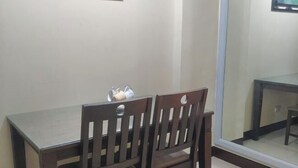 A dining area with a table and two chairs, a window with a view, and a framed picture on the wall. - Sarasota Genlex Condominium (Pasay)
