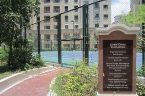 A tennis court with a fence and a sign detailing court regulations. - Sarasota Genlex Condominium (Pasay)