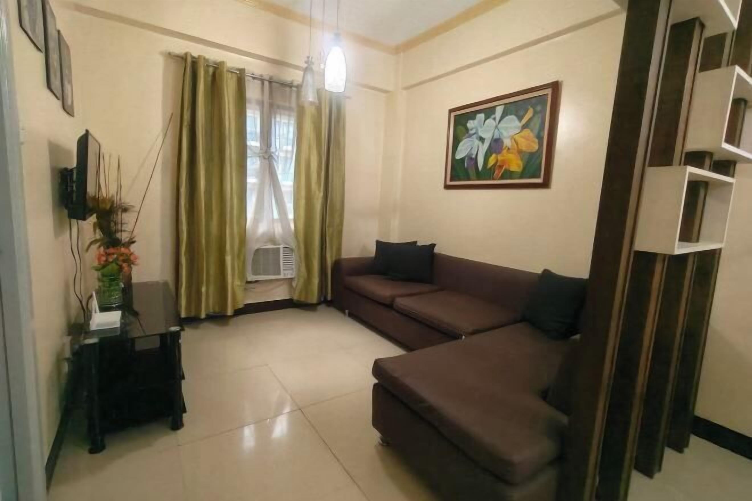 A living room with a brown sofa, a small table with a vase, and a painting on the wall.