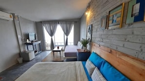 A room with a bed, a desk, a chair, a sofa, a TV, and a window with curtains. - Baanfahsai (Koh Larn)