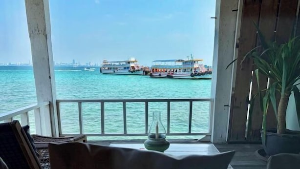 A balcony with a view of the sea and boats, a table with a candle, and a potted plant. - Baanfahsai (Koh Larn)