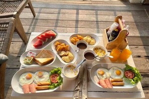A breakfast buffet with various food items and beverages on a wooden table. - Baanfahsai (Koh Larn)