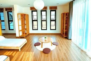 A room with a bed, a round table with chairs, and wooden shelving units.
