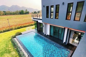 Ein modernes Gebäude mit Schwimmbad, großen Fenstern und Blick auf ein Feld.