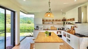 Een moderne keuken met een centraal eiland, witte kasten en uitzicht op een weelderige tuin.