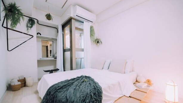 A modern bedroom with a bed, bedside table, and a nightstand with a lamp. - Minimalist Loft 7: Namba Compact Studio & 24/7 Gym (Osaka)