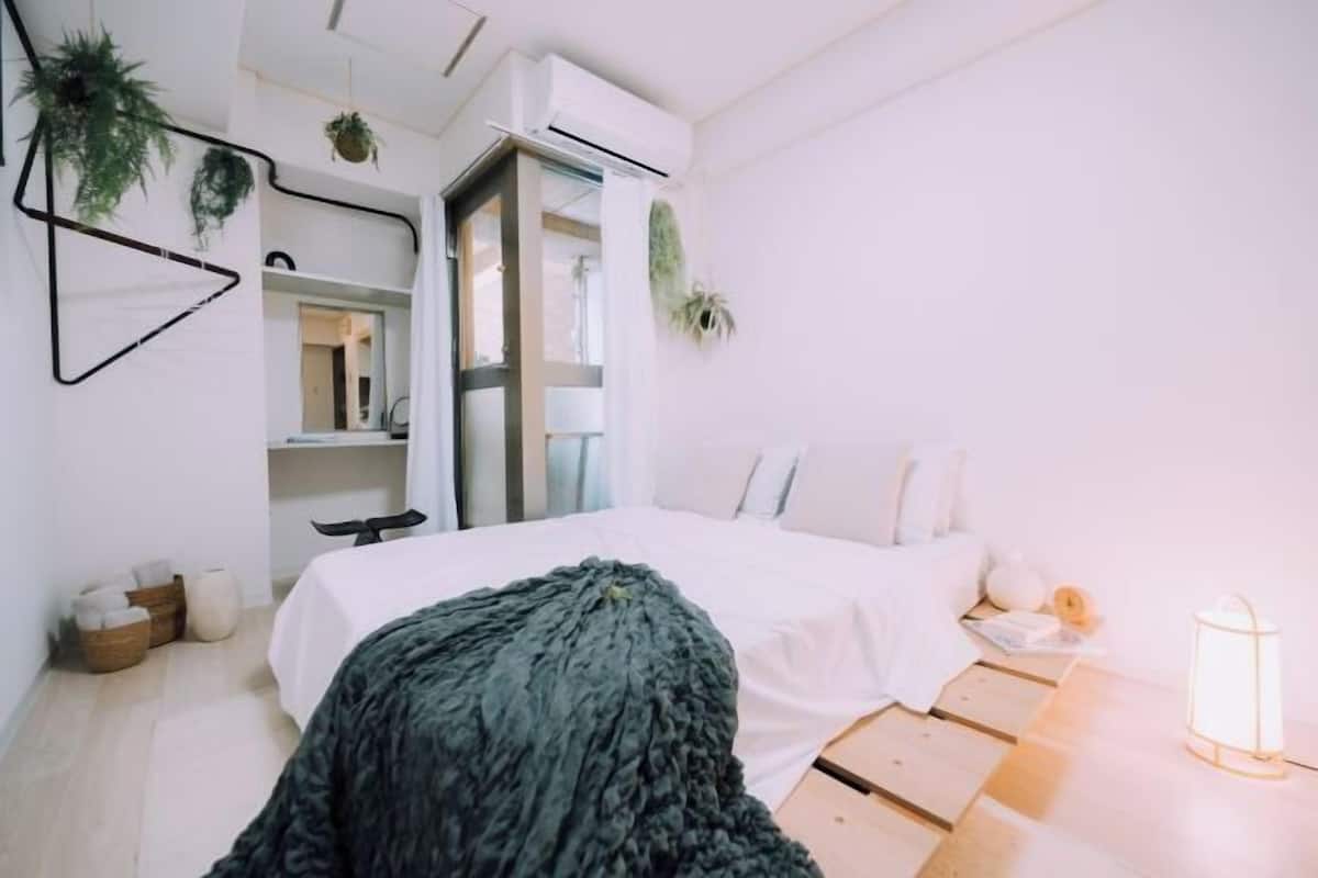 A modern bedroom with a bed, bedside table, lamp, and a view of the outdoors.