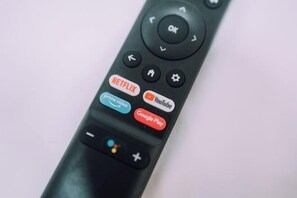 A close-up of a remote control with buttons for Netflix, Prime Video, YouTube, and Google Play. - Minimalist Loft 7: Namba Compact Studio & 24/7 Gym (Osaka)