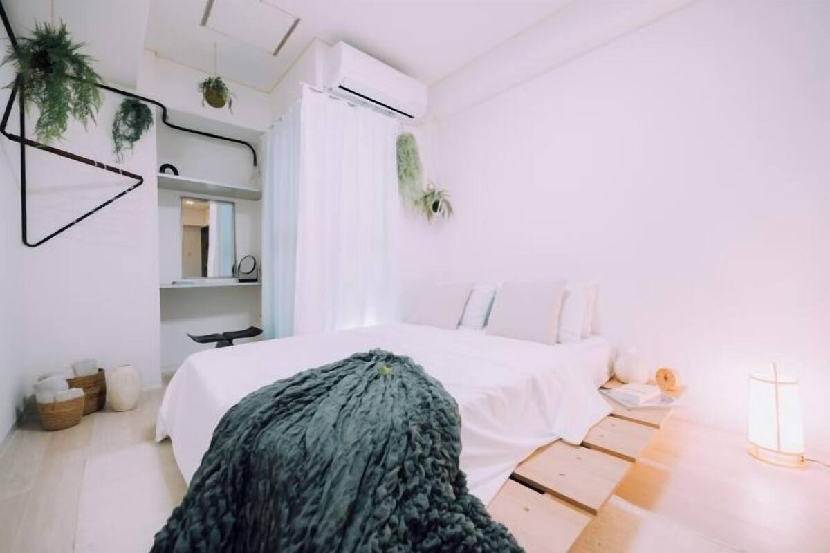 A modern bedroom with a bed, bedside table, and a hanging plant.