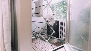 A room with a window, a metal drying rack, and an air conditioning unit. - Minimalist Loft 7: Namba Compact Studio & 24/7 Gym (Osaka)
