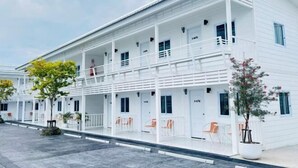 A white hotel with multiple floors, balconies, and outdoor seating areas. - Duangdeerojehouse (Chon Buri)