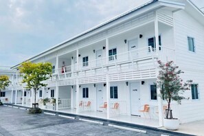 A white hotel with multiple floors, balconies, and outdoor seating areas. - Duangdeerojehouse (Chon Buri)