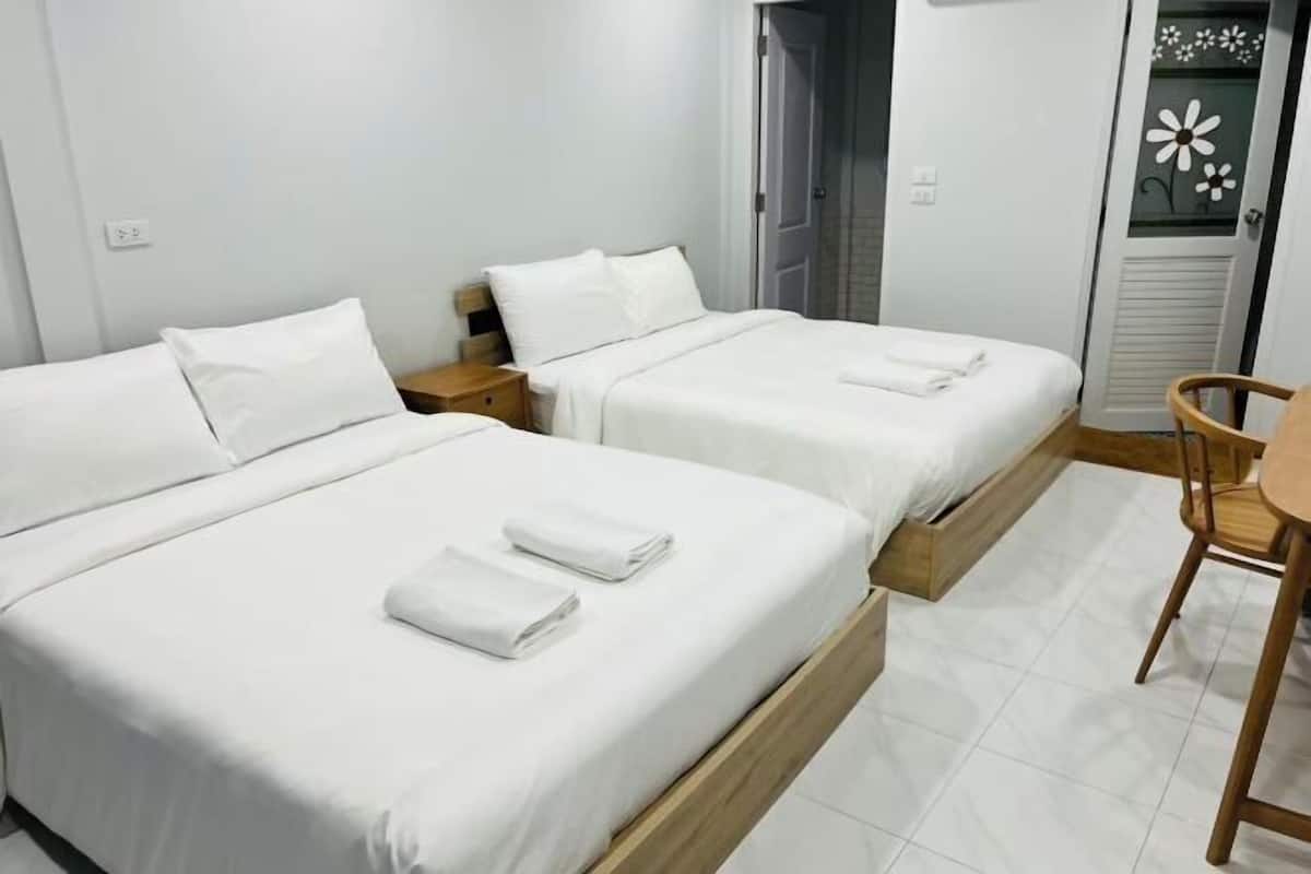 Ett hotellrum med två sängar, ett träbord vid sängen, en stol och ett litet bord.