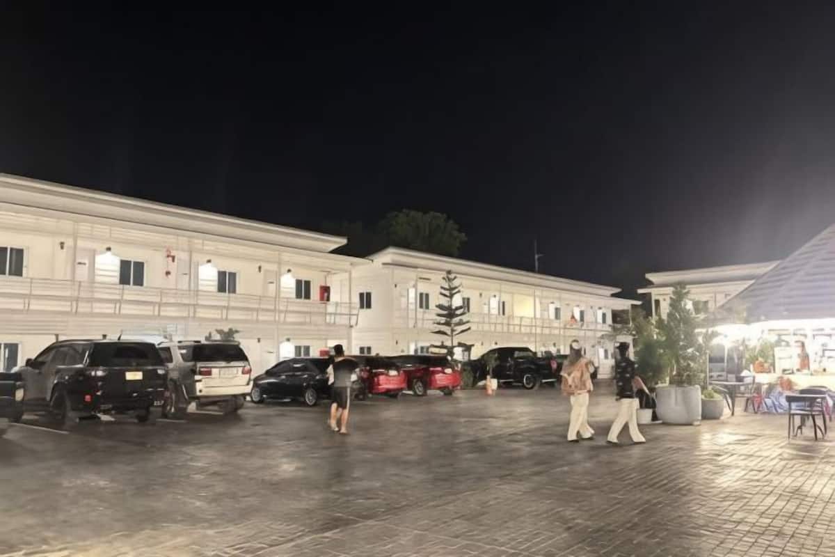 A building with multiple parking spaces and a few people walking around.