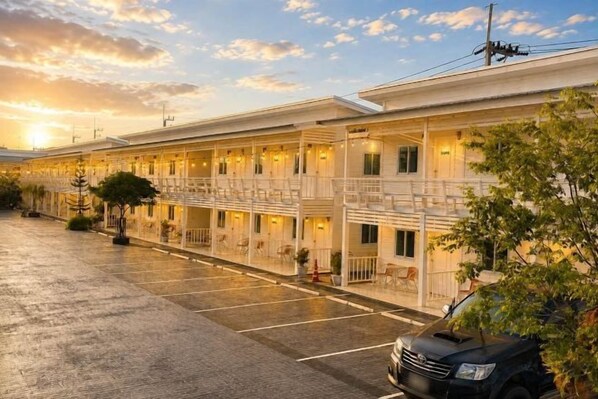 Un hotel con un espacio de estar cubierto al aire libre, varios balcones y un estacionamiento.