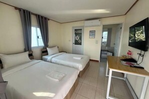 A hotel room with two beds, a TV, a desk, and a door leading to a bathroom. - Duangdeerojehouse (Chon Buri)