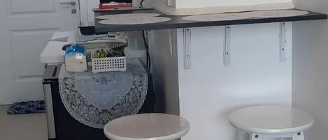 A kitchen area with a countertop, two stools, and a door.