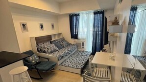 Une pièce de taille modeste comprenant un lit, un petit bureau, une chaise et un coin repas.