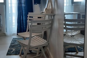 Ein Zimmer mit einem weißen Stuhl, der an eine Wand gelehnt ist, einem blauen Vorhang und einem gemusterten Teppich auf dem Boden.