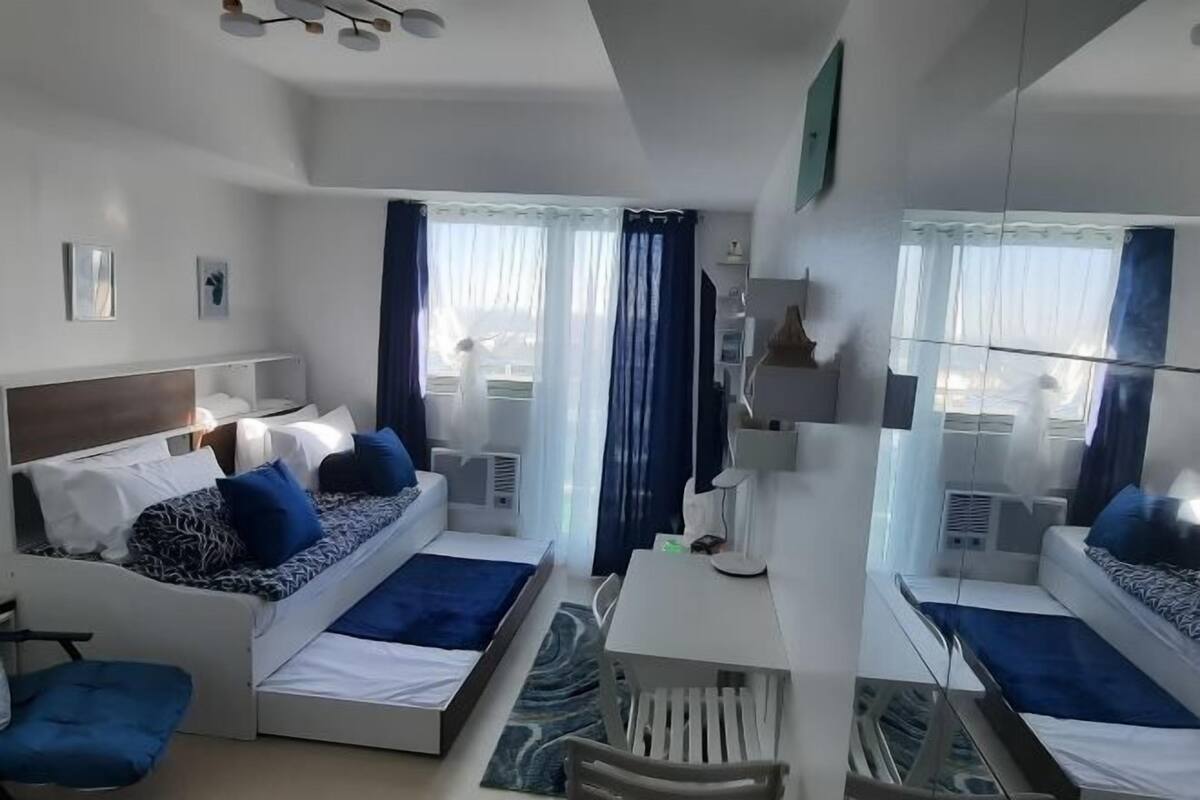 A modern hotel room with a bed, a desk, and a chair.
