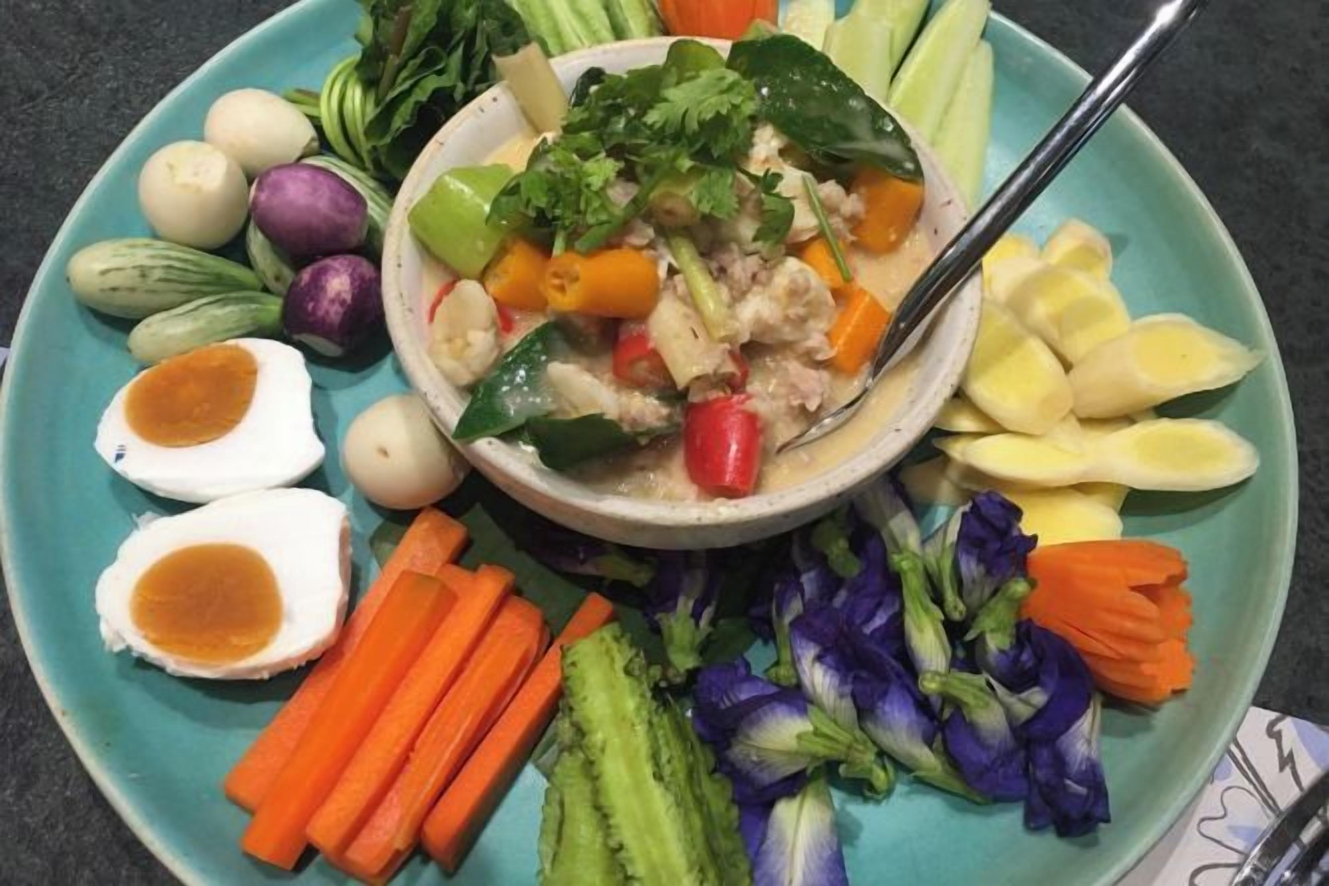 Une assiette contenant une soupe, des légumes et des œufs.