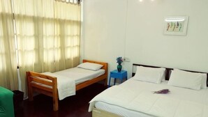 A room with two beds, a small table with a vase, and a wall-mounted light fixture. - Deng Ba Hostel Bangkok (Bangkok)