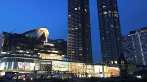 A modern hotel with a curved facade, multiple floors, and illuminated signage. - Deng Ba Hostel Bangkok (Bangkok)
