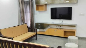 En moderne stue med sofa, fjernsyn og multimediemøbel.
