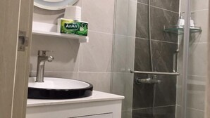 A bathroom with a sink, mirror, and shower.