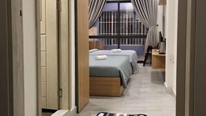 A hotel room with a bed, a desk, and a window with curtains.