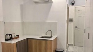 A small kitchenette with a sink, a coffee maker, and a trash bin.